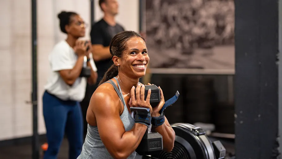 Woman smiling while lifting weights in gym.