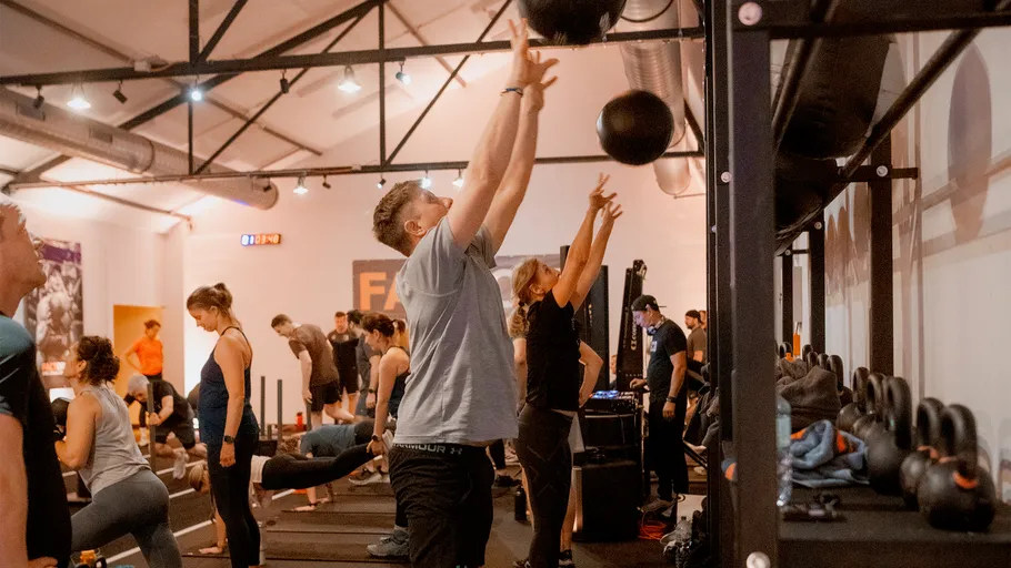 People working out with medicine balls indoors.