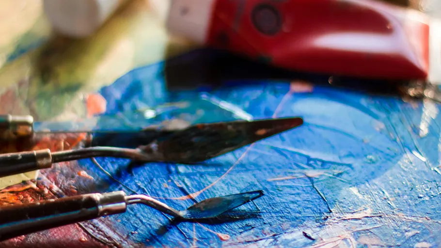 Palette knives on colorful paint surface.