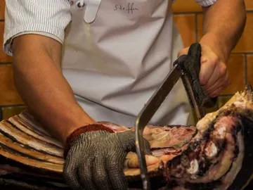 Meat is cut with a saw in a butcher shop.