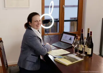 Eine Frau sitzt an einem Tisch, lächelt und arbeitet.