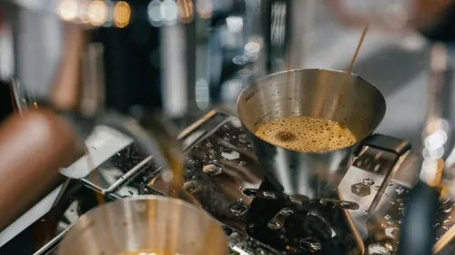 Espresso fließt in Metallbecher auf Maschine.