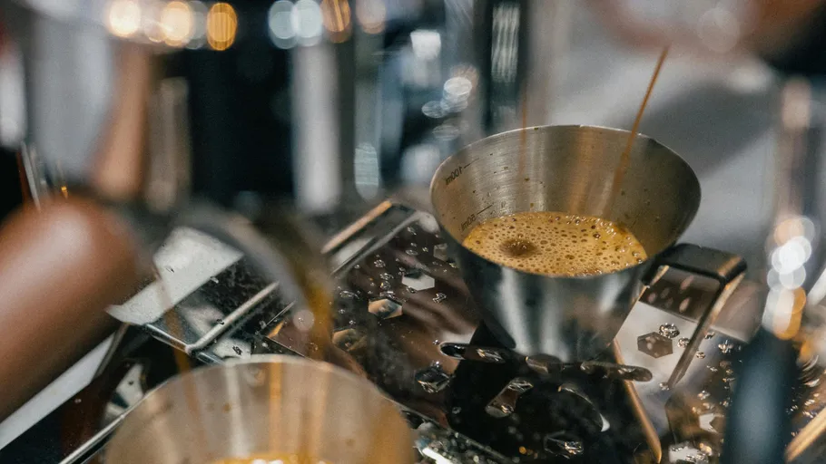 Espresso fließt in Metalltasse, Kaffeemaschine.
