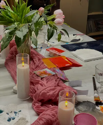 Tisch mit Tulpen, Kerzen und Malutensilien.