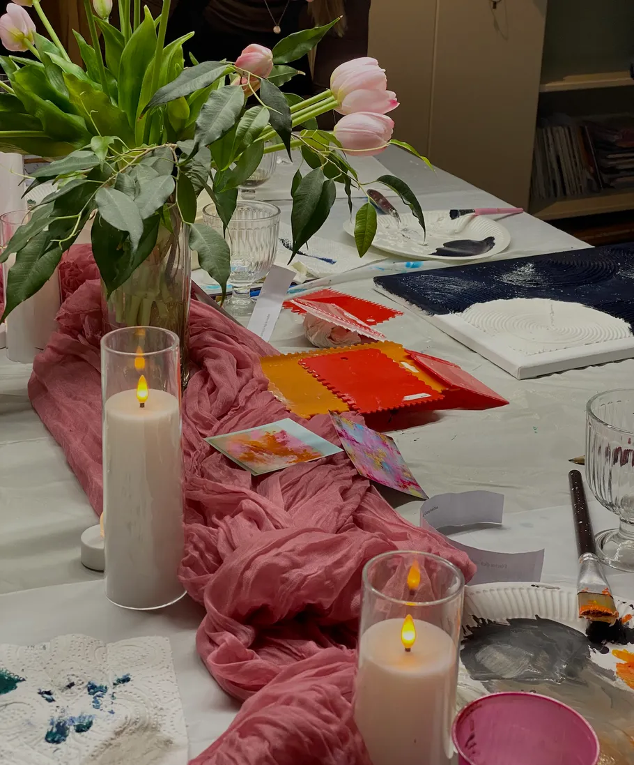 Tisch mit Tulpen, Kerzen und Malutensilien.