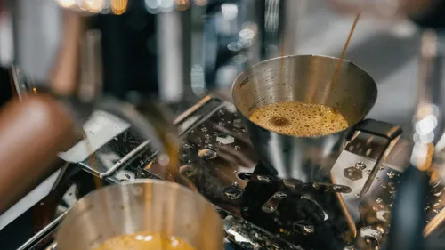 Espresso pouring into stainless steel cup.
