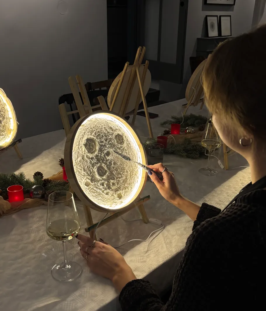 Person painting glowing moon art at table.