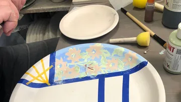 Hand bemalt einen Keramikteller auf Tisch.