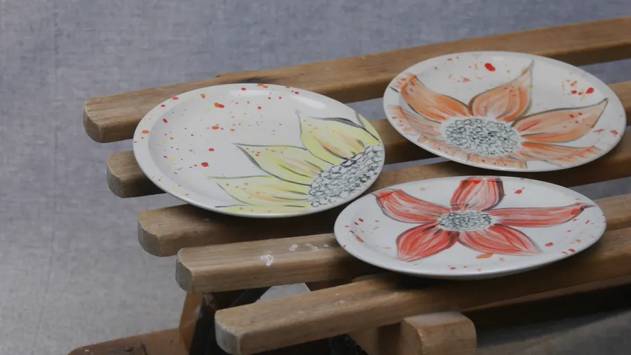 Three floral plates on a wooden rack.
