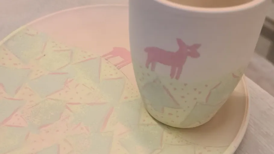 Dekorative Tasse auf gemustertem Teller, Pastellfarben.