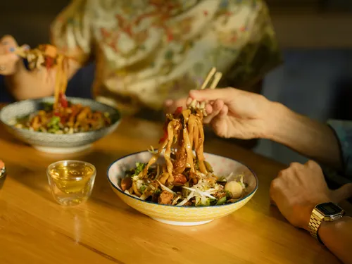 Pasta is removed from a bowl with chopsticks.