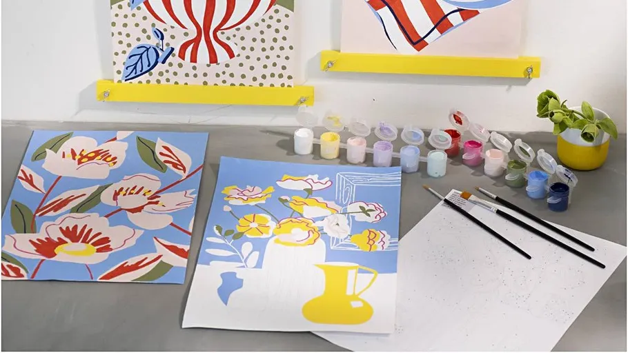 Art supplies and colorful paintings on table.