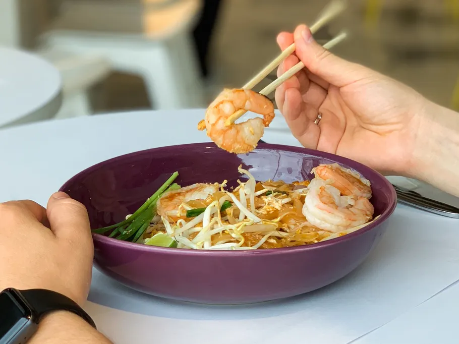 Shrimps are removed from a purple bowl with sticks.