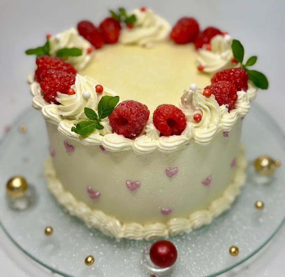 Cake with raspberries, cream, and mint leaves.