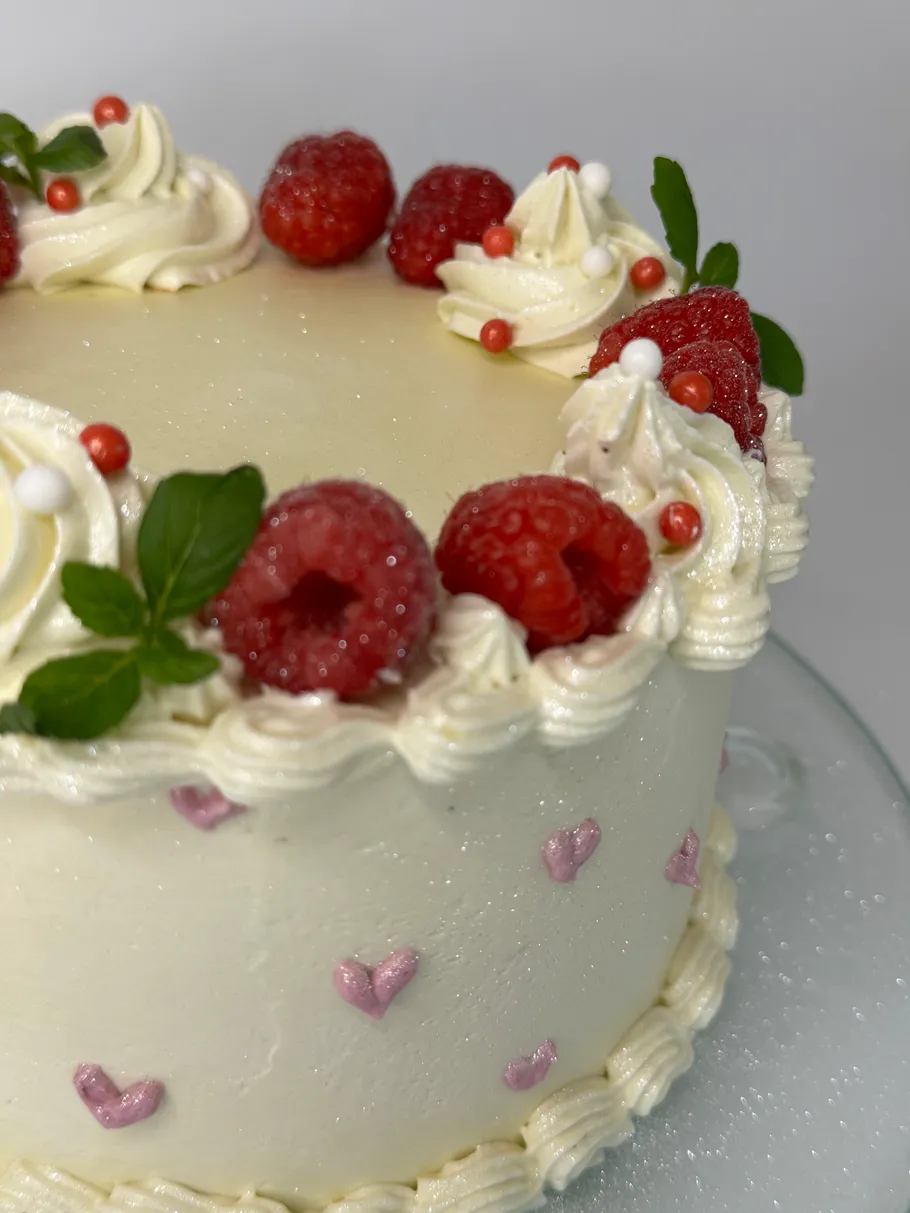 Cake with raspberries and cream decorations.