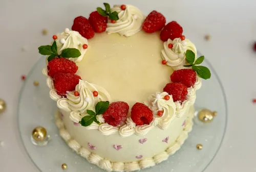 Decorated cake with raspberries on white surface.