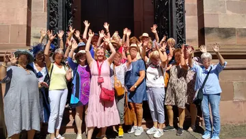 Group of women raising hands outside building.