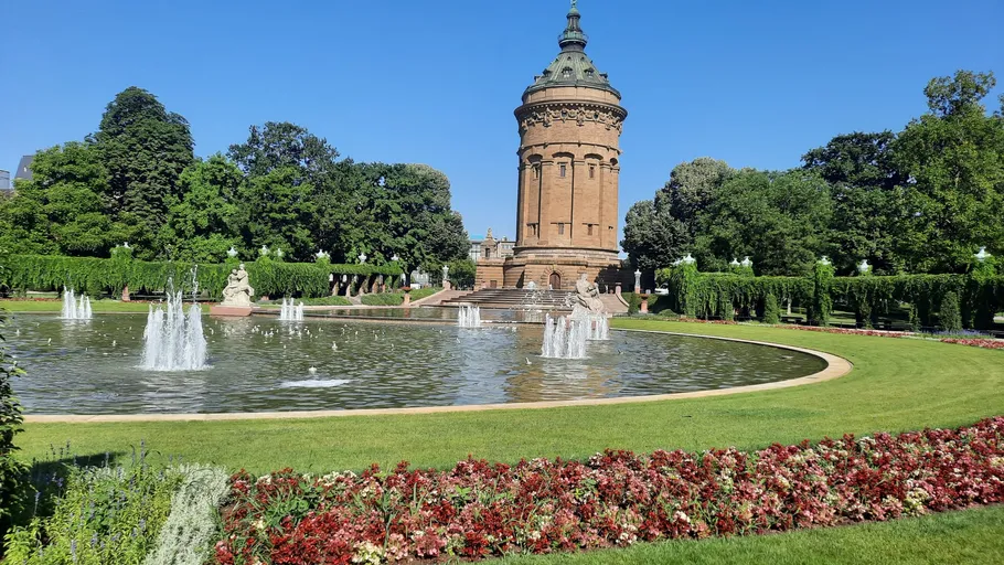 Historischer Turm mit Brunnen im üppigen Garten.