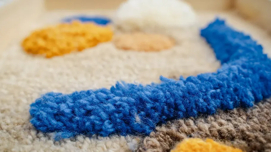 Bunte Wolltextur mit blauen, gelben Flecken.
