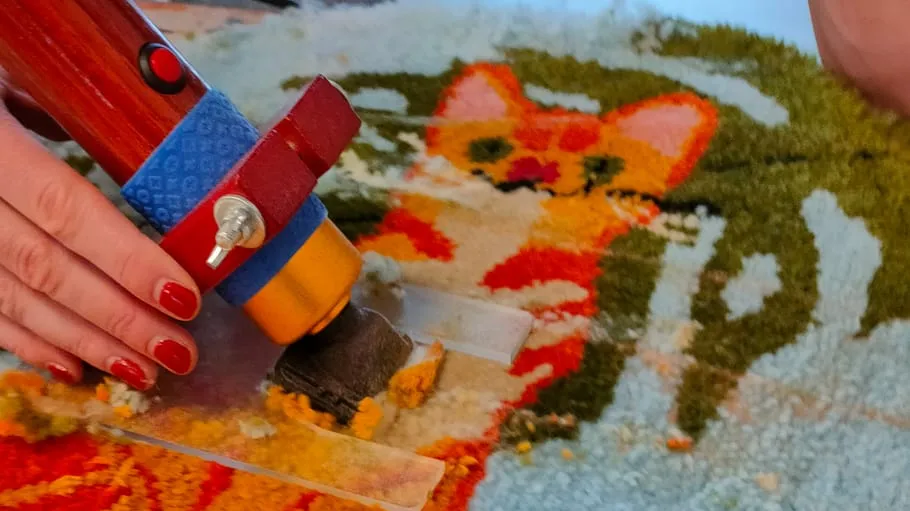 Hand tufting colorful cat design on carpet.