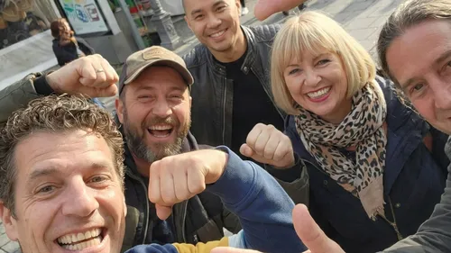 Gruppe von fünf Personen lächelt draußen.