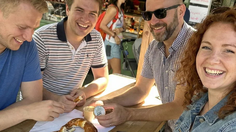 Group of people smiling, sharing pretzels outdoors.