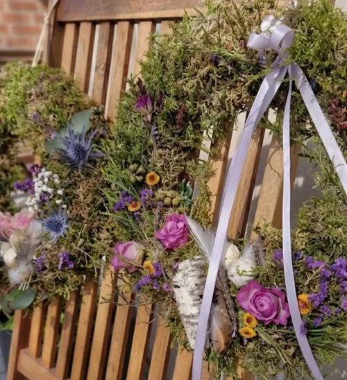 Floral wreaths with moss on wooden bench.