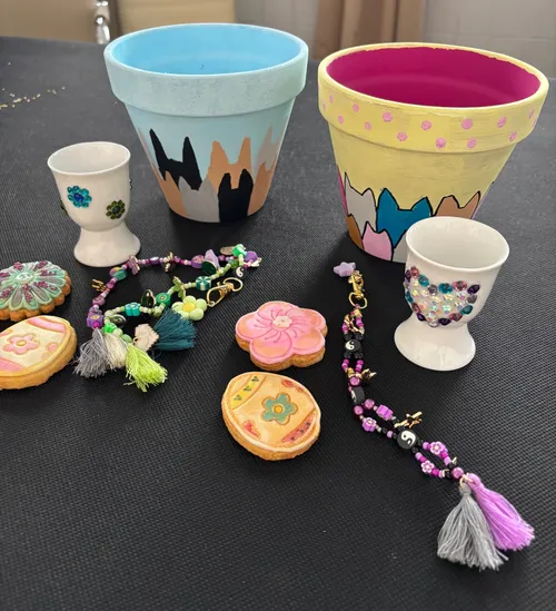Decorated pots, egg cups, cookies, bracelets on table.