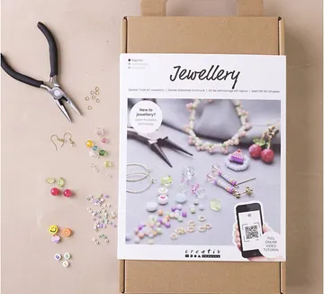 Jewelry making kit with tools and beads displayed.