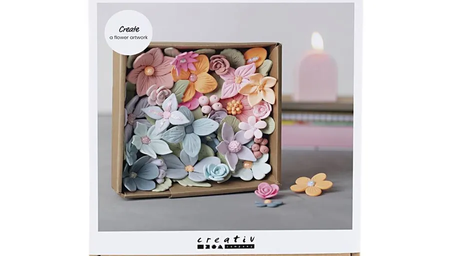 Box of colorful clay flowers on table.