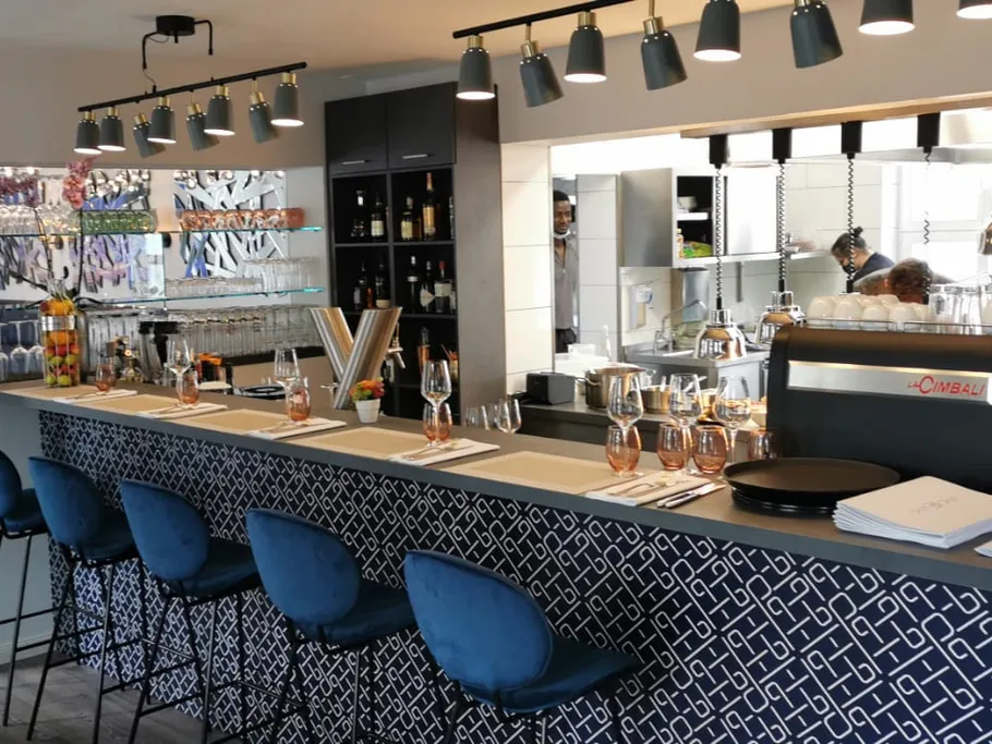 Moderne Bar mit Stühlen, Getränken und offener Küche.