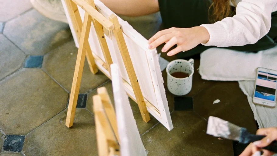 Person painting on small easel indoors.