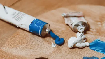 Blaue Farbe wird aus einer Tube auf eine Palette gedrückt.