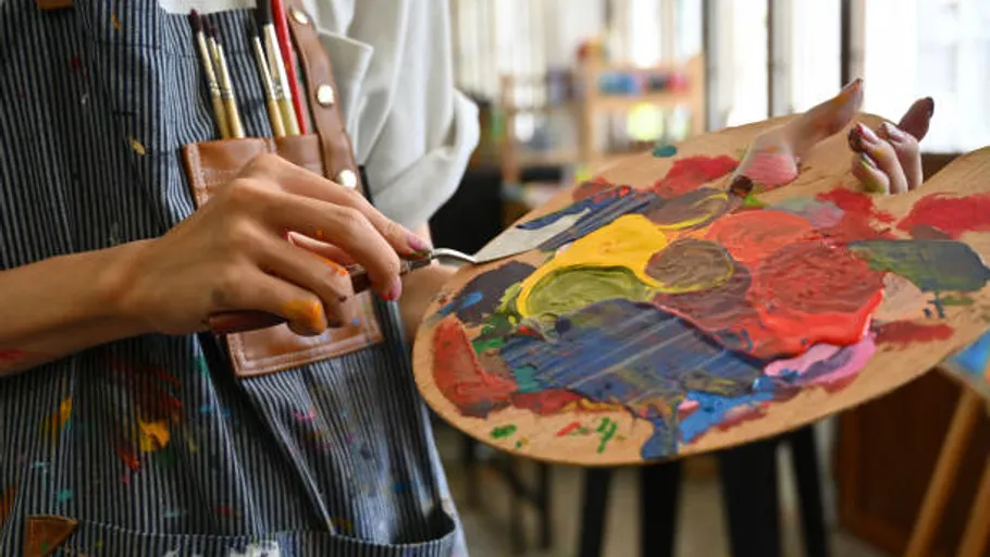 Artist mixing paint on palette in studio.