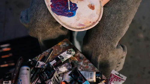 Person mischt Farben auf einer Palette drinnen.