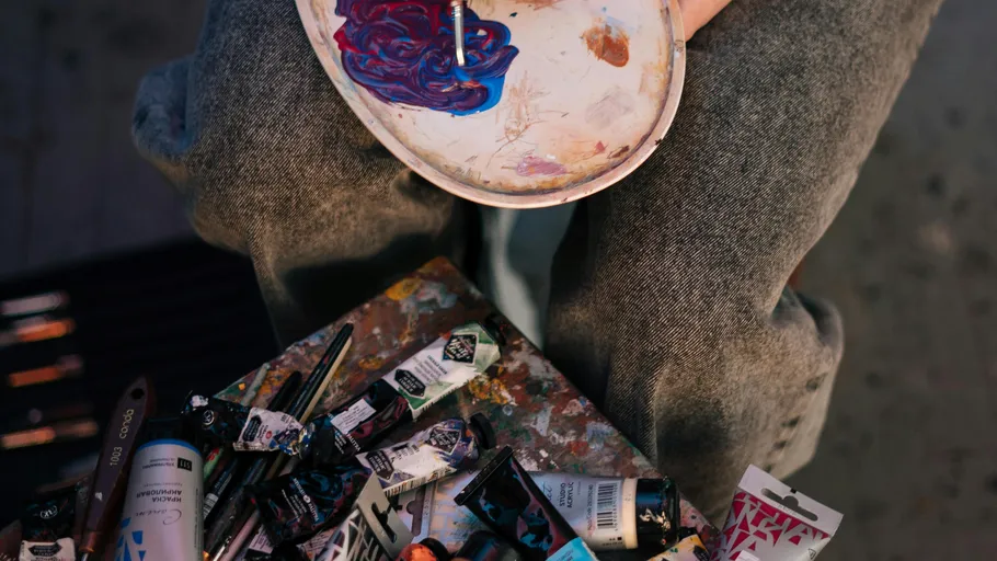 Person mischt Farben auf einer Palette drinnen.