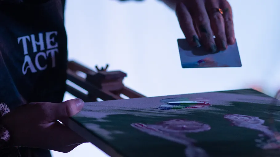 Painter using a card on canvas, studio setting.