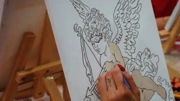 Hand painting cherub on canvas with easel.