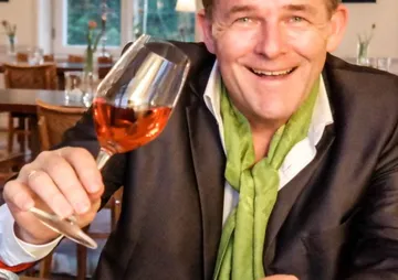 A man raises a wine glass in a restaurant.