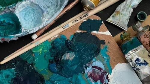 Palette with paint and brushes on table.