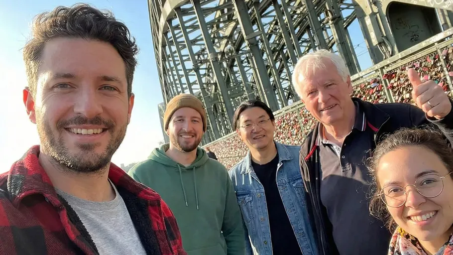 Five people smiling near bridge structure.