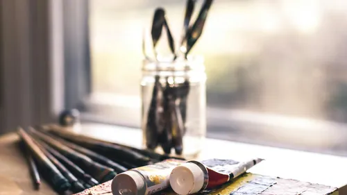 Paint brushes and tubes on a windowsill.