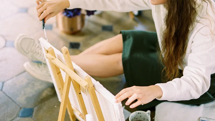 Woman painting on a canvas indoors.