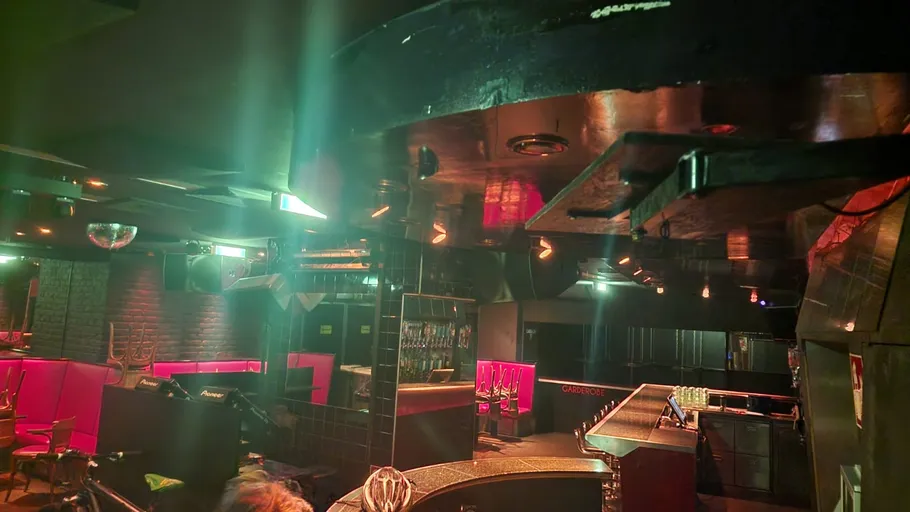 Empty bar with colorful lighting, reflecting disco ball.