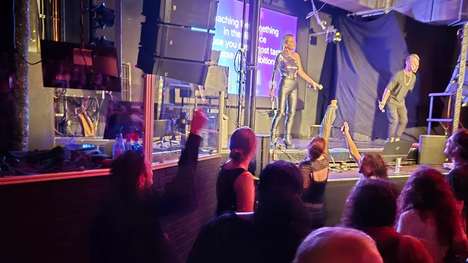 Performers singing on stage with audience watching.