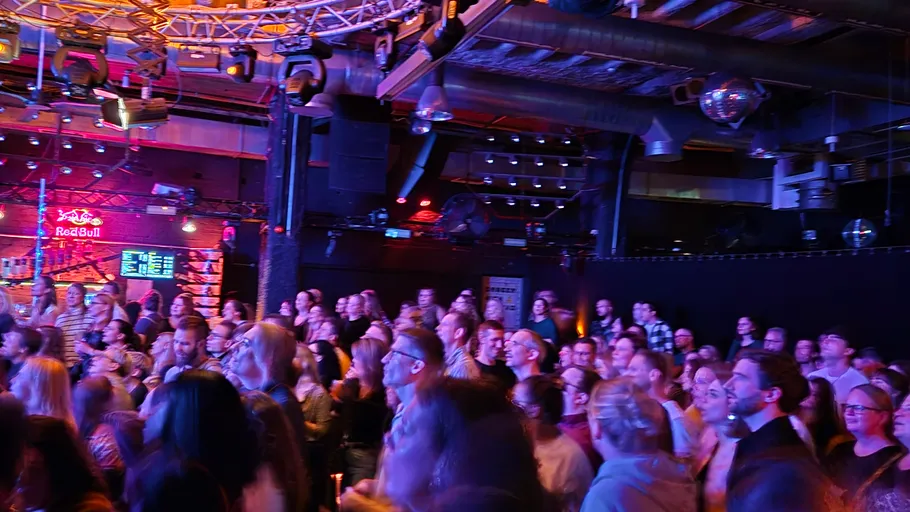 Menschenmenge genießt ein Konzert in dunkler Halle.