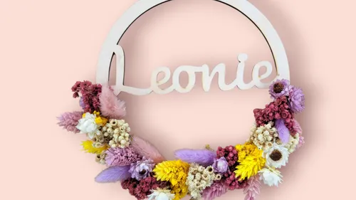 Blumenkranz mit dem Namen 'Leonie' auf rosa Hintergrund.