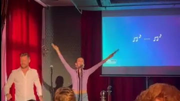 People singing on stage with microphone.