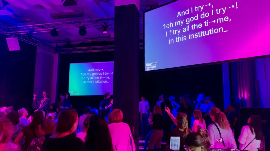 Crowd singing along with lyrics on screen.