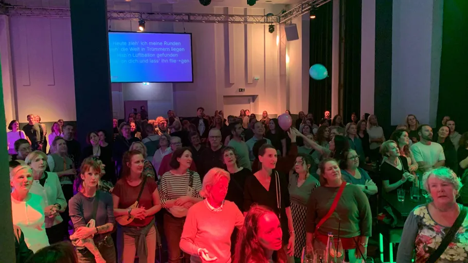 Crowd in a lively indoor concert setting.